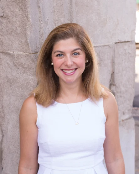 A photo Lauren Westendorf. She is standing outdoors and is wearing a white dress.