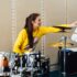 A woman is seated at a drum set practicing.