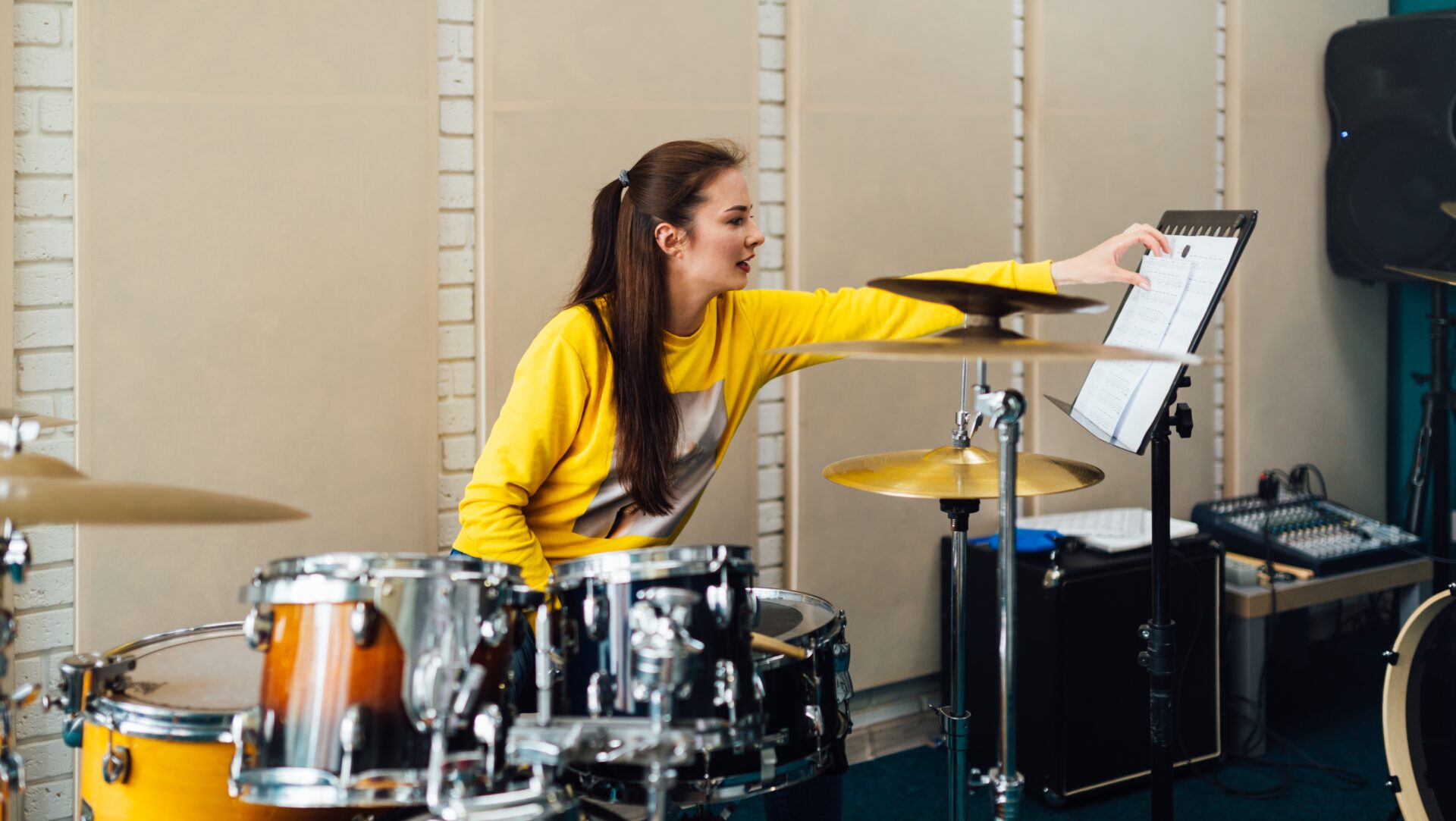 A woman is seated at a drum set practicing.