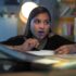 A girl sits at a desk thinking about what to write.