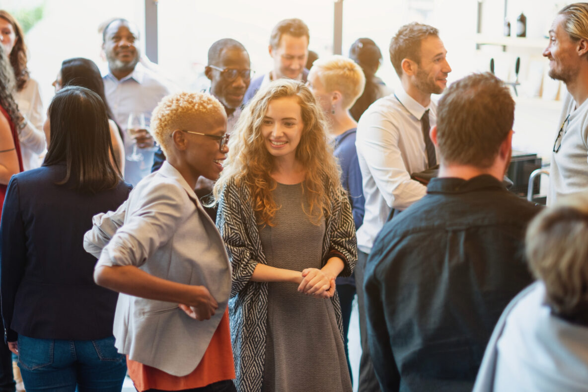 A large group of people are standing together engaged in conversation.