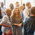 A large group of people are standing together engaged in conversation.